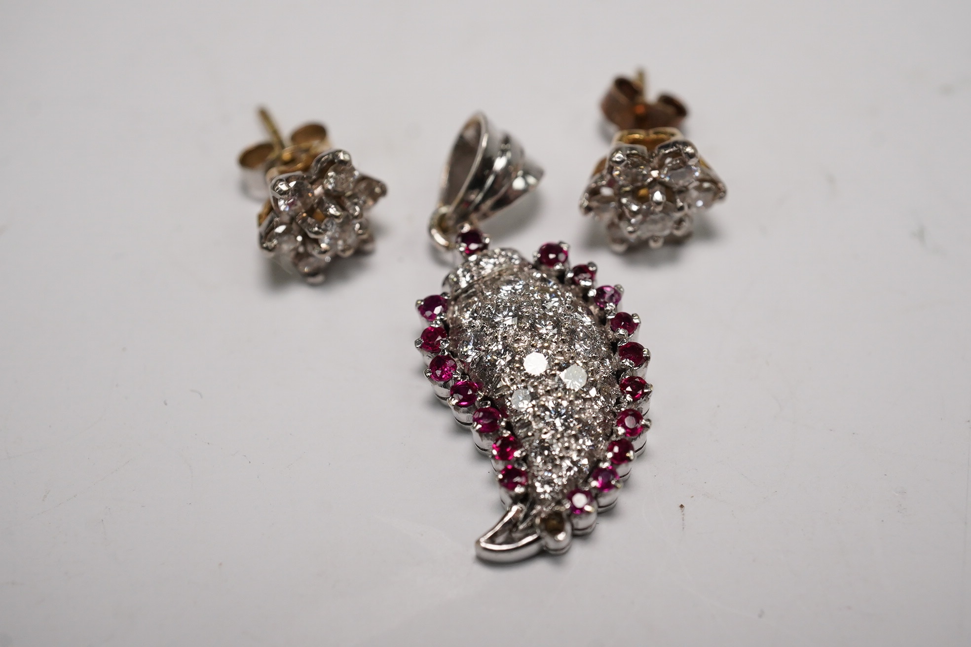 A white metal, diamond and ruby set pendant, 26mm and a pair of 9ct and diamond cluster set ear studs, gross weight 6.1 grams. Condition - fair to good